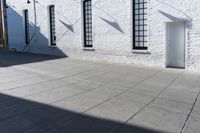 two windows that are on a white brick building with a gray sidewalk and a red fire hydrant