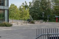 a white dog is walking down the concrete pathway towards a building with glass windows and trees