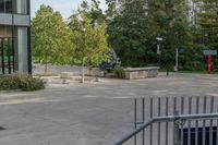 a white dog is walking down the concrete pathway towards a building with glass windows and trees