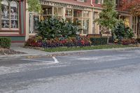 a white double decker parked next to an empty street side walk with many plant pots in it