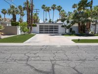 a white garage with three garages sitting next to palm trees and grass covered streets