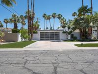 a white garage with three garages sitting next to palm trees and grass covered streets