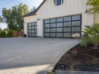 a large garage is painted white and the door is open to the outside area and plants in front