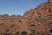 a white horse is standing alone in the mountain in the desert, in front of some red rocks