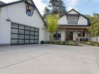 a white house with garage doors is seen from the outside out front on an open driveway