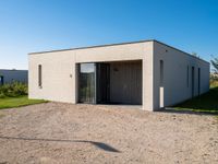 a white house with glass doors sits in the grass outside of the house on a sunny day