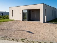 a white house with glass doors sits in the grass outside of the house on a sunny day