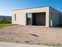 a white house with glass doors sits in the grass outside of the house on a sunny day