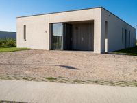 a white house with glass doors sits in the grass outside of the house on a sunny day