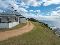 a white house sits next to the ocean and cliffs, overlooking the water's edge