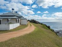 a white house sits next to the ocean and cliffs, overlooking the water's edge