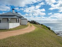 a white house sits next to the ocean and cliffs, overlooking the water's edge