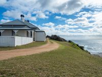 a white house sits next to the ocean and cliffs, overlooking the water's edge