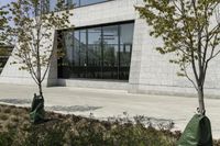 a white stone building with windows and a red fire hydrant on the sidewalk by some grass