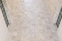 a room that is tiled in white tile with no one standing on the floor it's tile is not visible