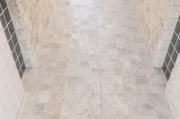 a room that is tiled in white tile with no one standing on the floor it's tile is not visible