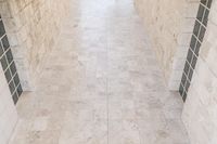 a room that is tiled in white tile with no one standing on the floor it's tile is not visible