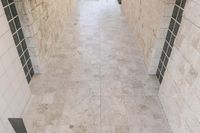 a room that is tiled in white tile with no one standing on the floor it's tile is not visible