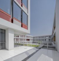 white tiles floor and railing inside the building under blue sky with clouds in background and courtyard area in foreground