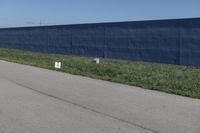 a row of white toilet tissue left on the side of the road near the wall