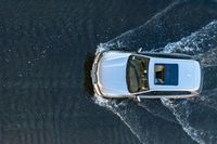 a white van on a lake splashing water with it's roof down looking to the water