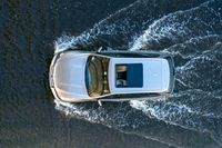 a white van on a lake splashing water with it's roof down looking to the water