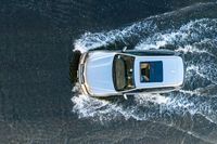 a white van on a lake splashing water with it's roof down looking to the water