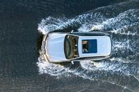 a white van on a lake splashing water with it's roof down looking to the water