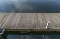 a small dock on the edge of a lake with lots of water and clouds in the background