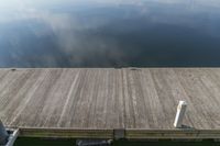 a small dock on the edge of a lake with lots of water and clouds in the background