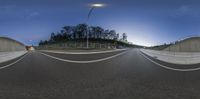 a 360 - view of a wide city road with traffic lights at night in the distance