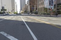 city street in a wide urban area surrounded by tall buildings and trees with traffic passing on the road