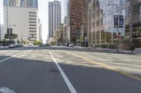 city street in a wide urban area surrounded by tall buildings and trees with traffic passing on the road