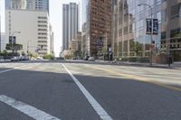 city street in a wide urban area surrounded by tall buildings and trees with traffic passing on the road