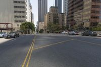 city street in a wide urban area surrounded by tall buildings and trees with traffic passing on the road