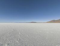 a view of a wide empty desert with no people on it's surface, and mountains in the background