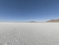 a view of a wide empty desert with no people on it's surface, and mountains in the background