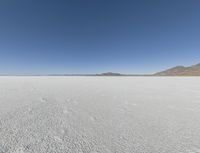 a view of a wide empty desert with no people on it's surface, and mountains in the background