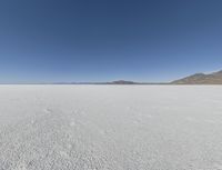 a view of a wide empty desert with no people on it's surface, and mountains in the background