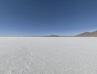 a view of a wide empty desert with no people on it's surface, and mountains in the background