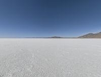 a view of a wide empty desert with no people on it's surface, and mountains in the background