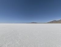 a view of a wide empty desert with no people on it's surface, and mountains in the background