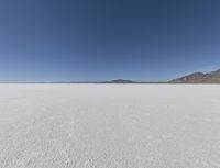 a view of a wide empty desert with no people on it's surface, and mountains in the background