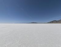 a view of a wide empty desert with no people on it's surface, and mountains in the background