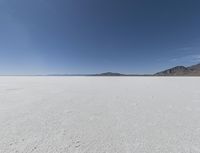 a view of a wide empty desert with no people on it's surface, and mountains in the background