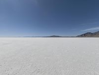 a view of a wide empty desert with no people on it's surface, and mountains in the background