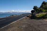 the view across a wide empty road in front of the ocean and the sea wall