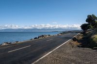 the view across a wide empty road in front of the ocean and the sea wall