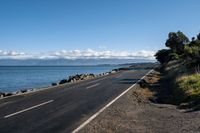 the view across a wide empty road in front of the ocean and the sea wall