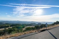 there are many clouds above the horizon and mountains in this picture of a wide open road